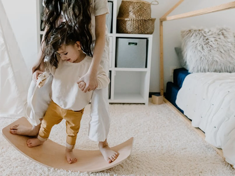 Kids playing on a balancing board in their beautifully carpeted bedroom